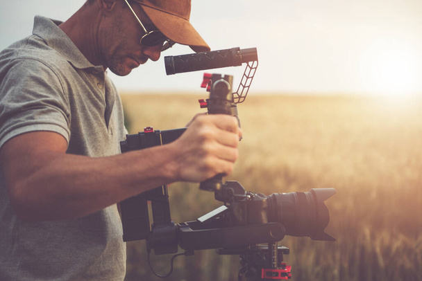 Valkoihoiset miehet Professional Camera Operator ottaen Video Shot käyttäen DSLR Moderni digitaalikamera ja Gimbal vakauttaja Vakaa kuvamateriaalia. Videoteema. - Valokuva, kuva
