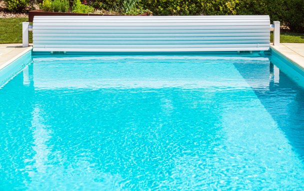 Nuevo obturador solar blanco de la cubierta de la piscina con manivela. Piscina abierta. - Foto, imagen
