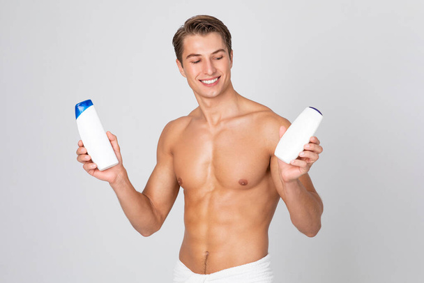 Schöner junger Kerl steht mit Shampoo in den Händen - Foto, Bild