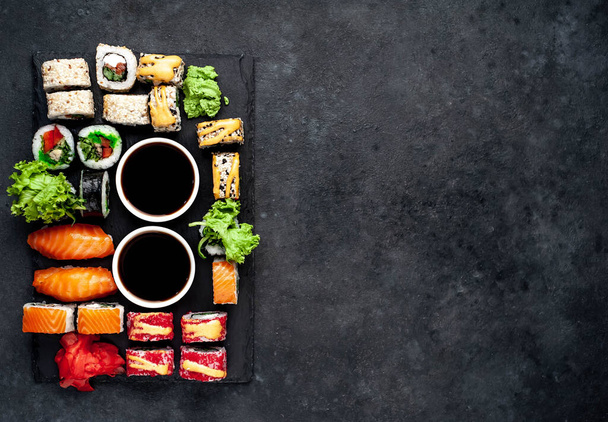 Készlet válogatott sushi szójaszósszal sötét alapon  - Fotó, kép