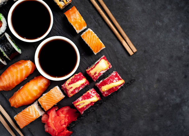 Készlete válogatott sushi evőpálcikával, szójaszósz sötét alapon  - Fotó, kép