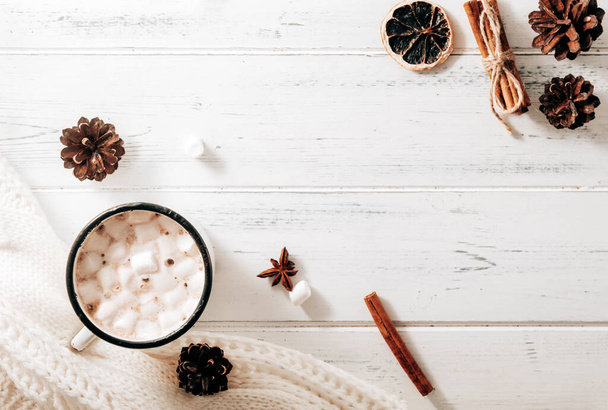 cocoa mug with marshmallows, hot chocolate, white sweater, cones, cinnamon sticks, star anise on a white wooden background, hot winter drink, place for inscription - Φωτογραφία, εικόνα