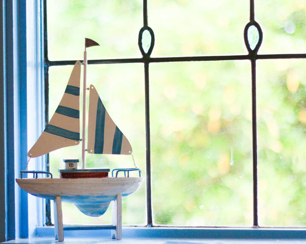 Ornamento veleiro na frente da janela de luz de chumbo na casa de praia. Barcos são um grampo da decoração de casa de férias costeiras
! - Foto, Imagem