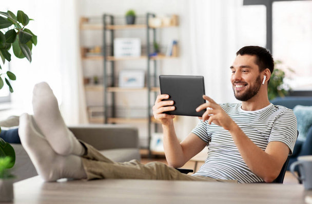 happy man with tablet pc and earphones at home - Fotó, kép