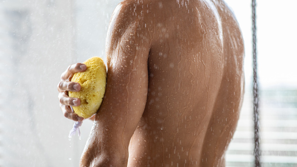 Schöner junger Mann wäscht sich die Arme mit Schwamm - Foto, Bild