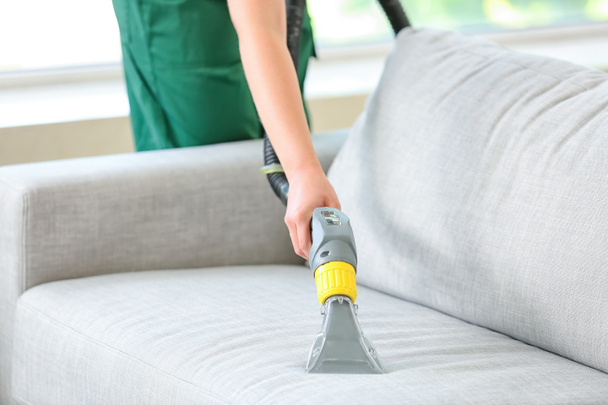 Dry cleaner's employee removing dirt from sofa in house - Valokuva, kuva