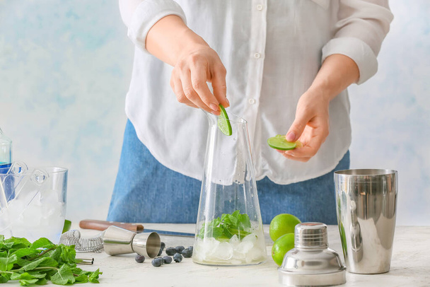 Woman making tasty mojito cocktail at table - 写真・画像