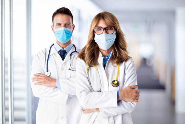 Shot of female and male doctors standing together  while looking at camera. Medical team. Doctors wearing face masks for prevention. - Photo, Image
