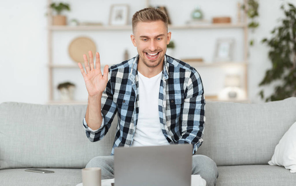 Ευτυχισμένος τύπος που χρησιμοποιεί τον υπολογιστή για βιντεοκλήση και χαιρετισμό - Φωτογραφία, εικόνα