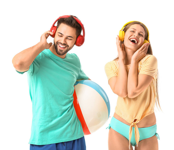 Young couple with headphones and inflatable ball on white background - Photo, Image