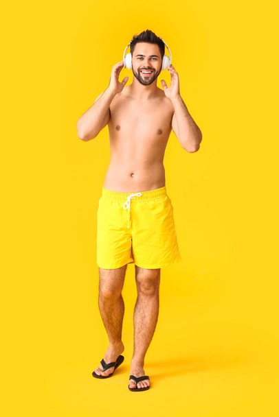 Young man with headphones on color background - Foto, afbeelding