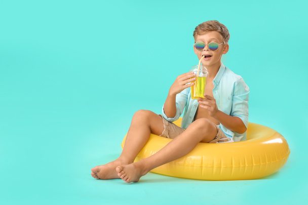 Roztomilý chlapeček s nafukovacím kroužkem a koktejlem na barevném pozadí - Fotografie, Obrázek