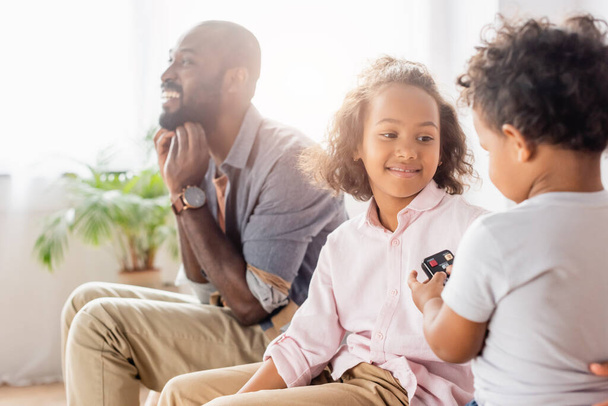 excited african american man sitting near daughter and son at home - Photo, image
