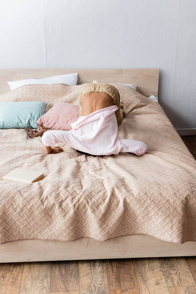 Africano americano menina escondendo cabeça enquanto se divertindo na cama em casa - Foto, Imagem