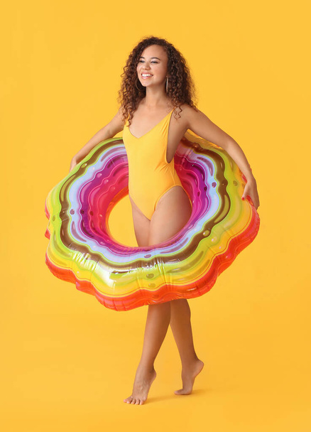 Hermosa mujer afroamericana joven con anillo inflable sobre fondo de color - Foto, imagen