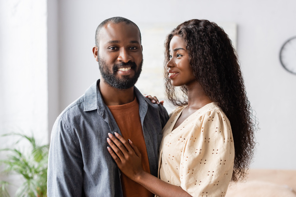 young african american woman touching husband looking at camera at home - Fotó, kép