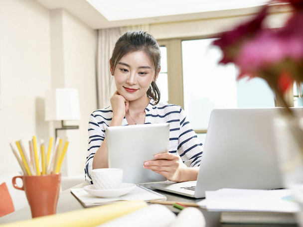 giovane donna d'affari asiatica che lavora a casa con computer portatile e tablet digitale - Foto, immagini
