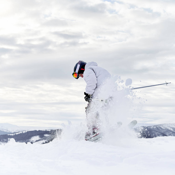 Concept de sports d'hiver. Skier conduisant des tours dans les montagnes en saison hivernale, fusionnant avec l'arrière-plan. Station de ski à grand temps - Photo, image