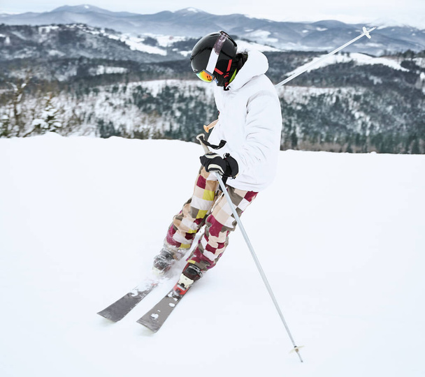 Изображение лыжника в лыжном снаряжении, захваченного в движении, делающего трюк в снежных горах в полную длину. Красивый пейзаж на заднем плане. Концепция зимнего спорта - Фото, изображение