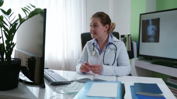 servizio sanitario, medico donna consulta un paziente online che mostra i sintomi della malattia su una radiografia che comunica tramite video comunicazione su computer seduto in studio medico - Filmati, video