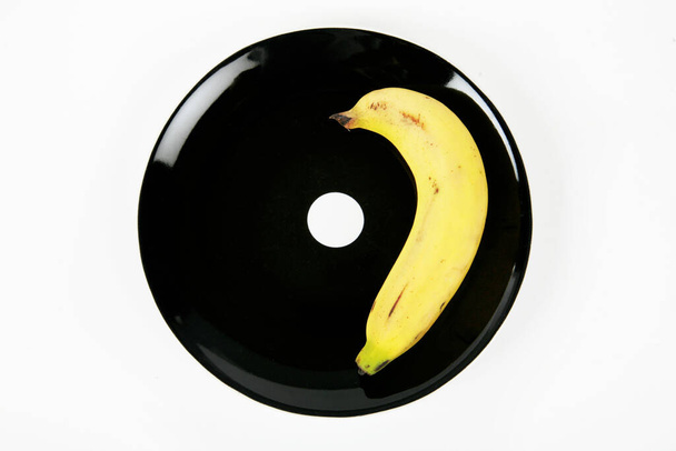 banana on black plate on a white background  - Φωτογραφία, εικόνα