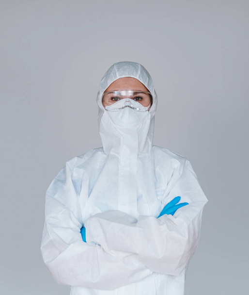 Women doctor wearing protective suit to fight coronavirus pandemic covid-2019. Protective suit, googles, gloves, respirator. - Photo, Image