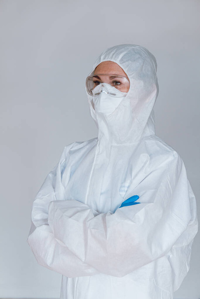 Women doctor wearing protective suit to fight coronavirus pandemic covid-2019. Protective suit, googles, gloves, respirator. - Foto, Imagem