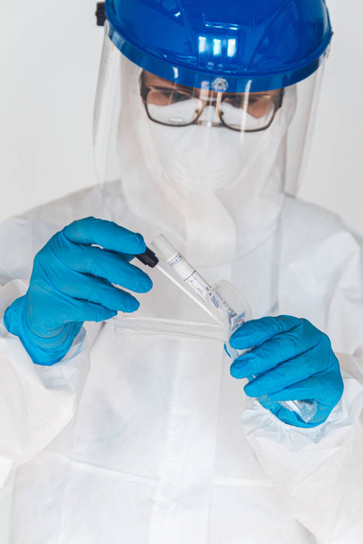 Female doctor or nurse in protective suit takes a specimen swab to further check for coronavirus in the laboratory. - Photo, Image