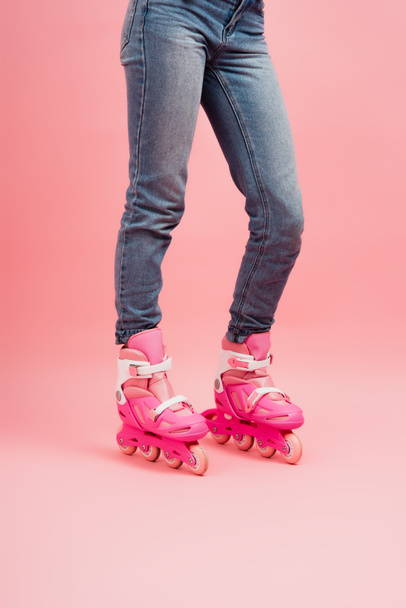 cropped view of woman in jeans and rollers skates on pink - Фото, зображення