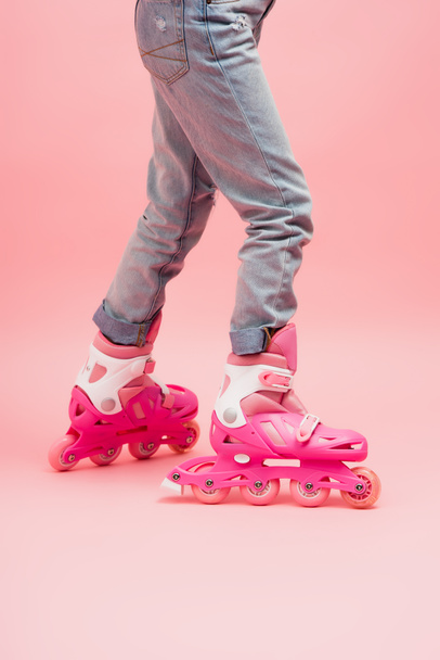 cropped view of child in jeans and rolling skates on pink - Fotoğraf, Görsel