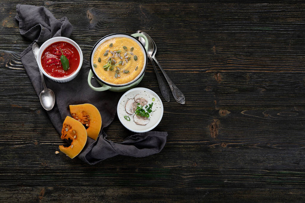 Vegetables cream soups on dark wooden background. Top view with copy space - Фото, зображення