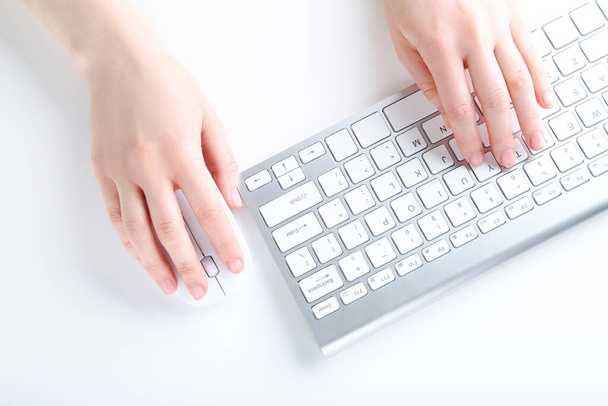 Female hands typing on computer keyboard and holding mouse on white background - Фото, изображение