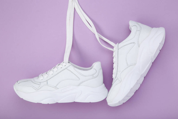 Pair of hanging white shoes on purple background - Fotografie, Obrázek