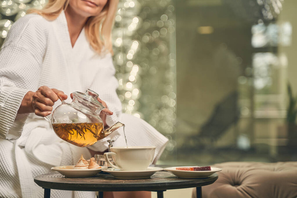 Female pouring green tea in a cup at the breakfast - Foto, Bild