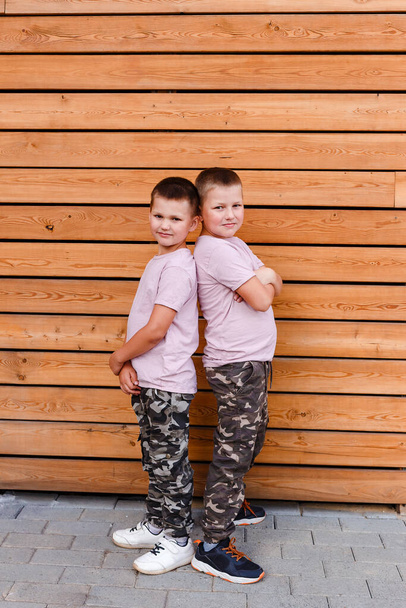 two boys of eight years stand with each other's backs and look into the camera in full height - Foto, immagini
