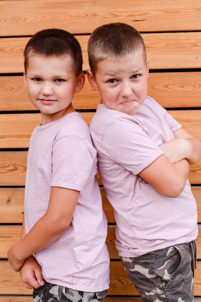 two cheerful brothers stand with their backs to each other and look into the camera. funny faces - Photo, image