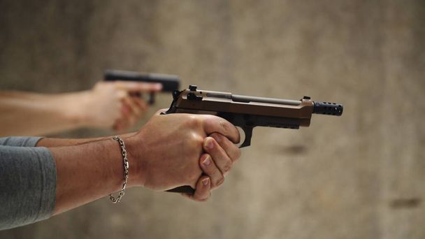 Deux hommes s'entraînent à tirer avec un pistolet à main au champ de tir  - Photo, image