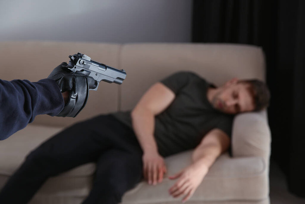 Man with gun and his victim in room, closeup. Dangerous criminal - Fotoğraf, Görsel