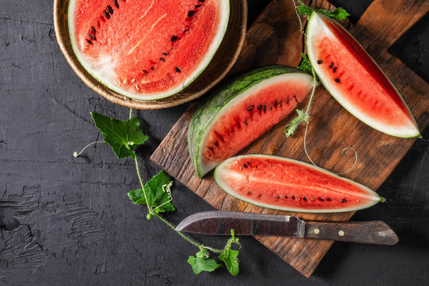 Watermelon slices cut in half on a wooden cutting board. - Фото, зображення