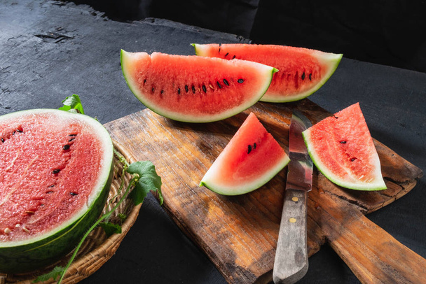 Watermelon slices cut in half on a wooden cutting board. - Fotó, kép