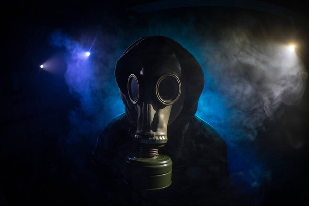 Milieuramp. Post-apocalyptische overlevende met gasmasker op een donkere achtergrond. Dramatisch portret van een man met een gasmasker. Middelen voor stralingsbescherming. Selectieve focus - Foto, afbeelding