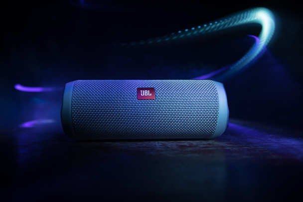 BAKU. AZERBAIJAN - 28.07.2020: JBL Flip 4 Bluetooth Speaker close up shot on wooden table with colorful lights and fog on background. Selective focus - Photo, Image