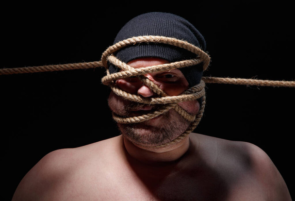 Imagem de homem gordo ligado com corda no rosto
 - Foto, Imagem