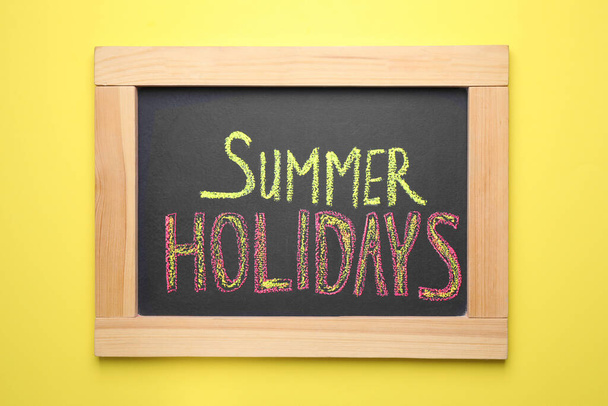 Chalkboard with phrase SUMMER HOLIDAYS on yellow background, top view. School's out - Foto, afbeelding