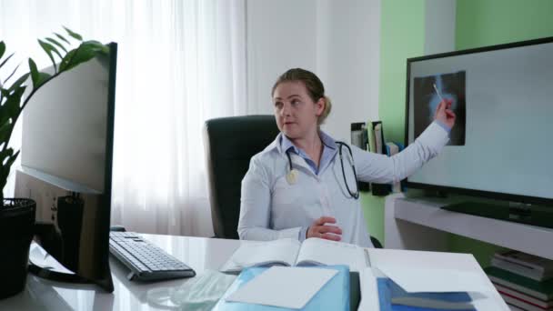 assistenza sanitaria, medico femminile consulta un paziente online raccontando i sintomi della malattia utilizzando una radiografia utilizzando il collegamento video su computer e webcam - Filmati, video