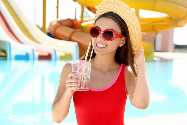Woman with glass of refreshing drink in water park - Fotó, kép