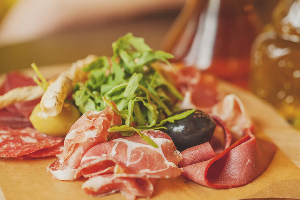 Charcuterie board con jamón de jamón de jamón, salami, hierbas y antipasti de oliva. Platos gourmet - Foto, imagen