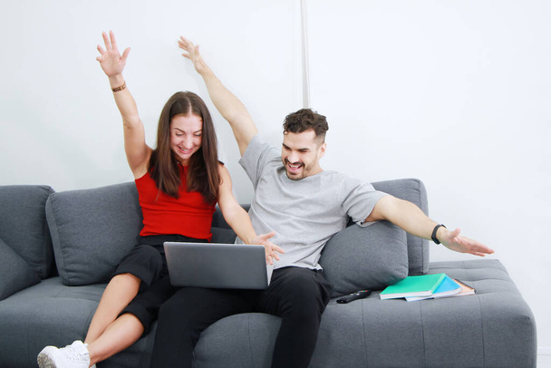 Smiling Caucasian Couple love relaxing and funny in online games with laptop in social media technology on sofa in living room. Work from home and Married family lifestyle on holiday Concept. - Photo, Image