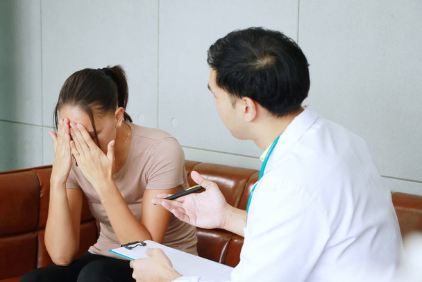 Joven psiquiatra masculino asiático es especialista en psiquiatría está asesorando y escuchando los problemas de la mujer caucásica Paciente con depresión en el tratamiento clínico de los síntomas emocionales. - Foto, Imagen