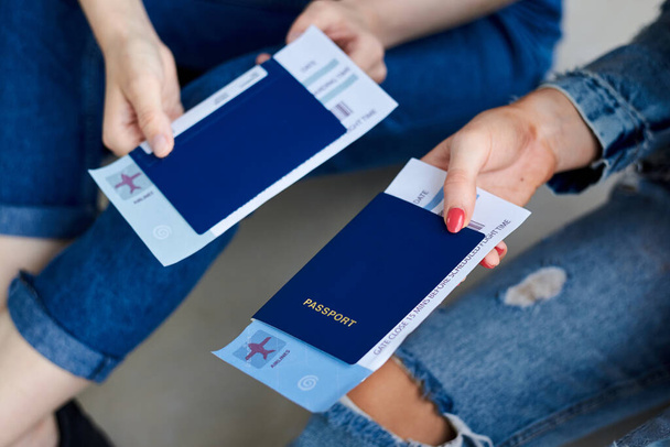 Foto de close-up de mãos femininas, segurando passaportes internacionais azuis com bilhetes de embarque dentro. Documentos de viagem aérea
. - Foto, Imagem